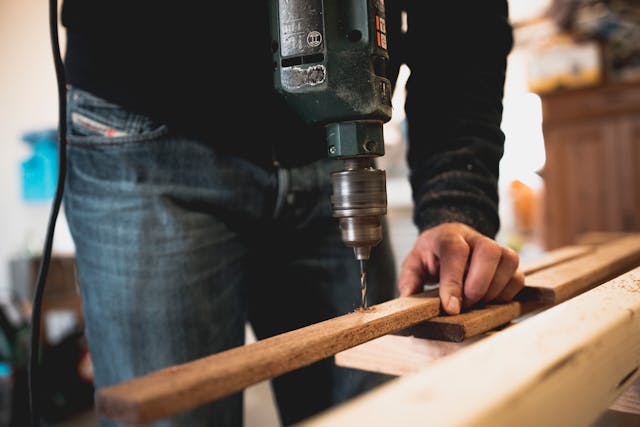 person drilling a hole through a piece of wood