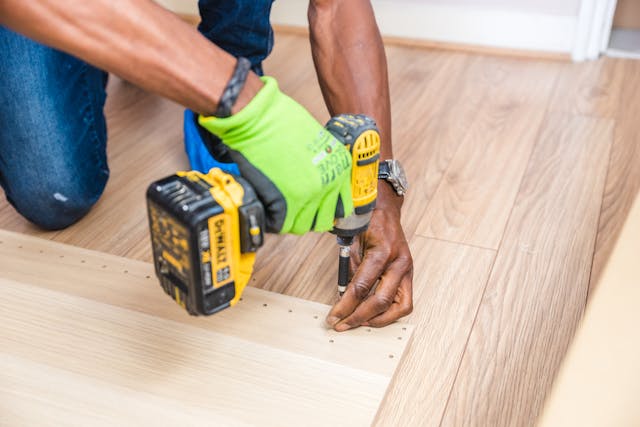 person using a drill to screw something into wooden planks