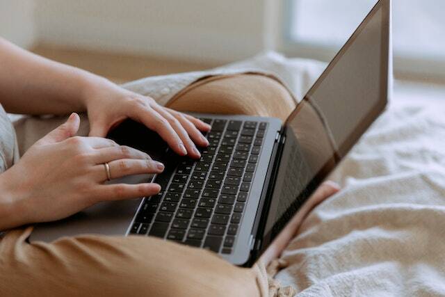 person-using-laptop-while-sitting-on-bed