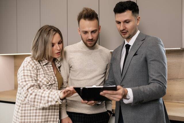 property-manager-looking-at-a-document-on-a-clipboard-with-two-people