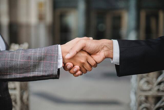 two-business-people-shaking-hands-one-wearing-a-grey-business-suit-and-the-other-wearing-a-black-suit