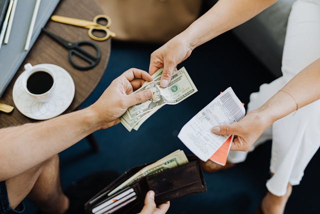 two people exchanging money with one person holding an open wallet