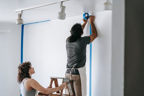 two-people-wearing-aprons-getting-a-wall-ready-to-paint